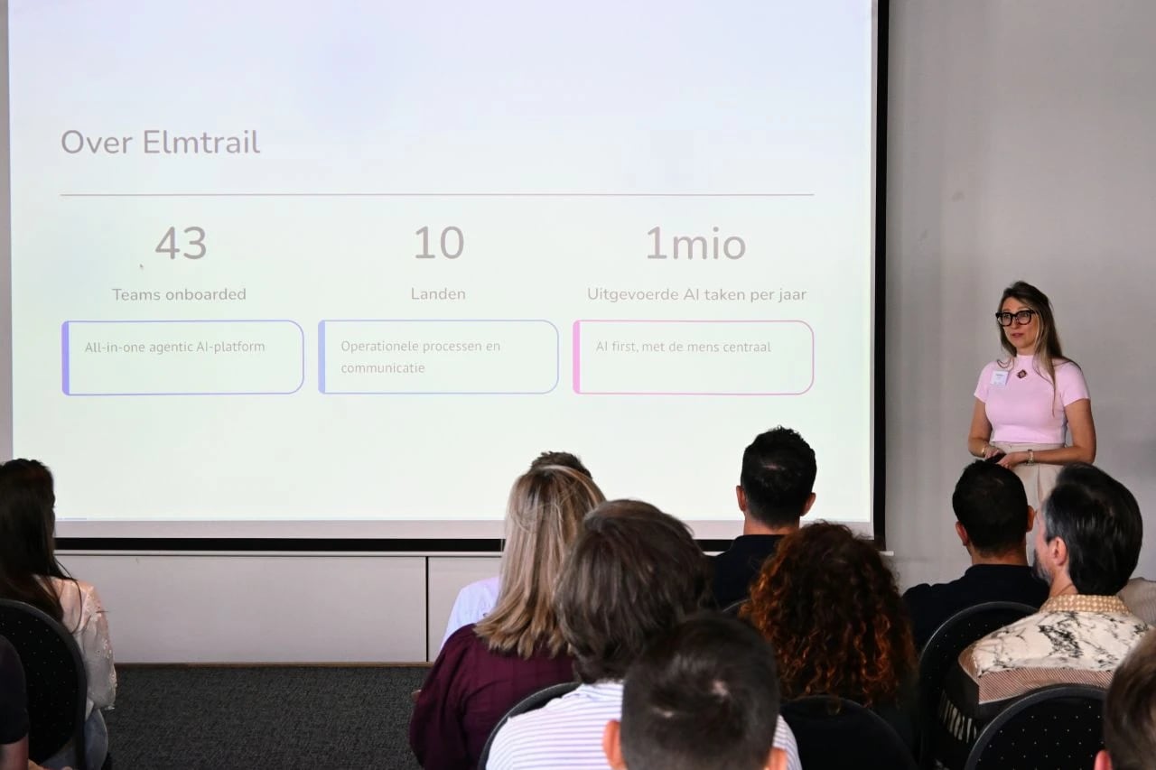An Elmtrail session: a speaker in front of a slide about Elmtrail, with a room of attendees